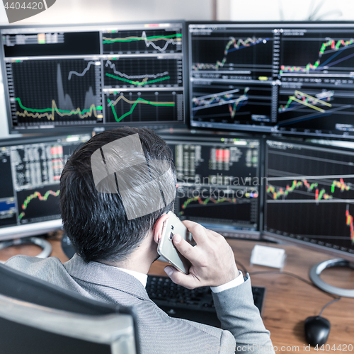 Image of Over the shoulder view of computer screens and stock broker trading online.