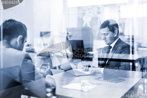 Image of Two young businessmen using laptop computer at business meeting.