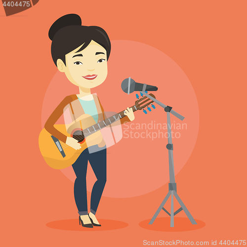 Image of Woman singing in microphone and playing guitar.