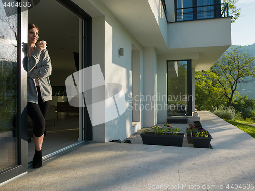 Image of woman drinking coffee in front of her luxury home villa