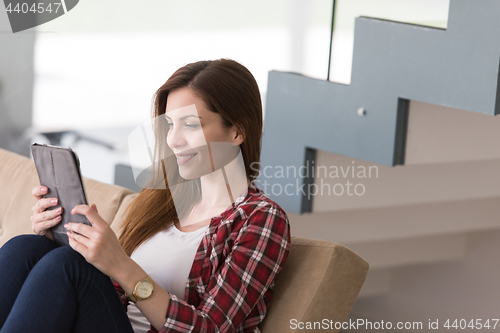 Image of woman sitting on sofa with tablet computer