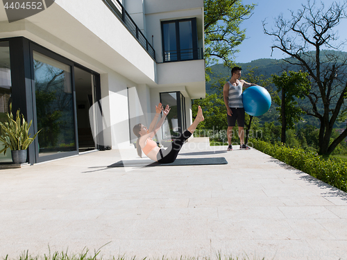 Image of woman and personal trainer doing exercise with pilates ball