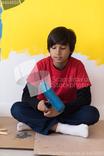 Image of young boy painter resting after painting the wall