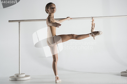 Image of The girl is training near the ballet barre.