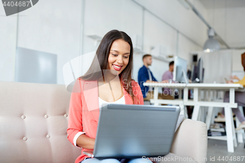 Image of happy woman with laptop working at office