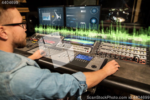 Image of man at mixing console in music recording studio