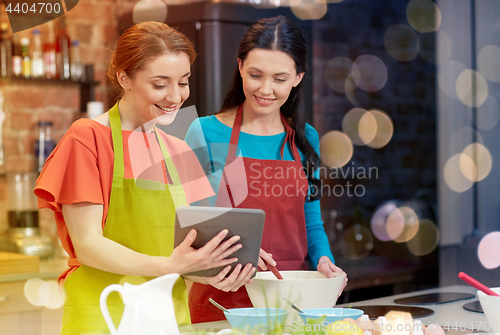 Image of happy women with tablet pc cooking in kitchen