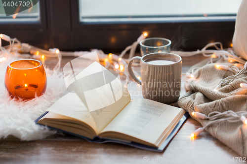 Image of book and coffee or hot chocolate on window sill