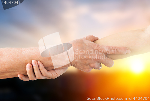 Image of close up of senior and young woman holding hands