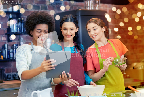 Image of happy women with tablet pc cooking in kitchen