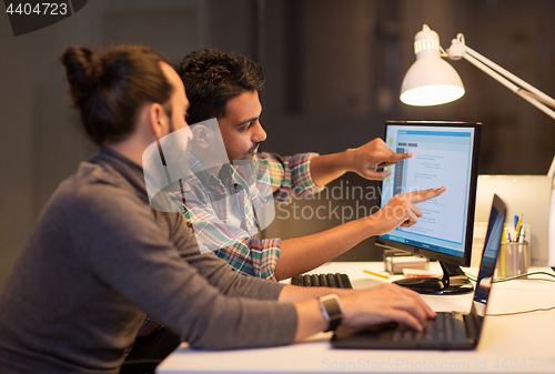 Image of creative team with computer working late at office