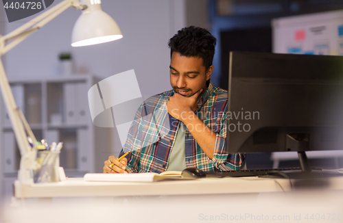 Image of creative man with notebook working at night office