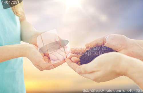 Image of close up of father and daughter hands holding soil