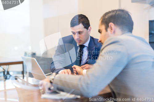 Image of Two young businessmen using laptop computer at business meeting.