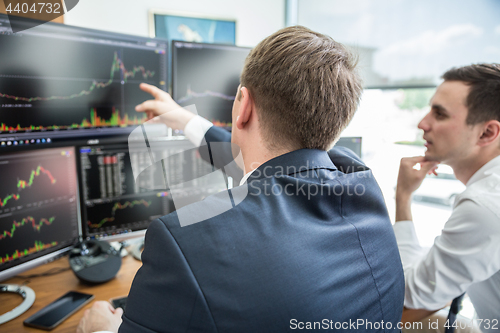 Image of Stock brokers looking at computer screens, trading online.