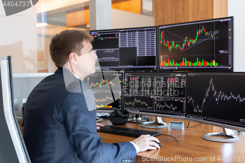 Image of Stock trader looking at computer screens in trdading office.