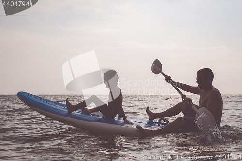 Image of Father and son playing football on the beach at the day time.