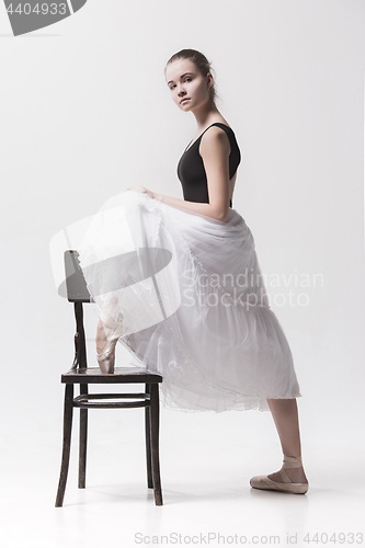 Image of The teen ballerina in white pack posing near chair