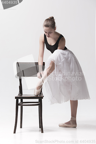 Image of The teen ballerina in white pack posing near chair