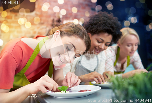 Image of happy women cooking and decorating dishes