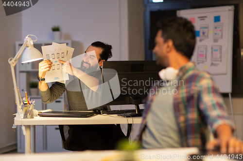 Image of creative man showing papers to colleague at office