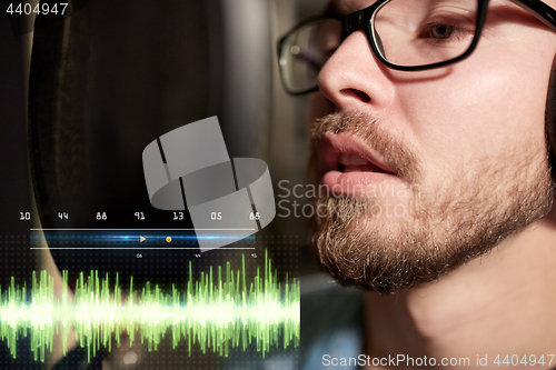 Image of man with headphones singing at recording studio