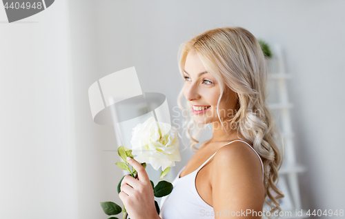 Image of woman in underwear with rose flower at window