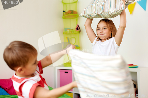 Image of kids playing and fighting by pillows at home