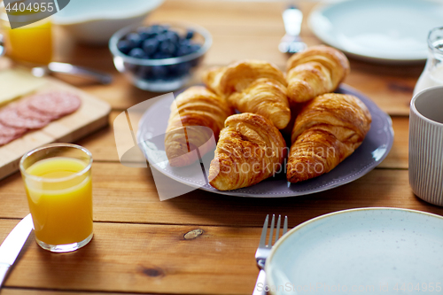 Image of plate of croissants on wooden table at breakfast