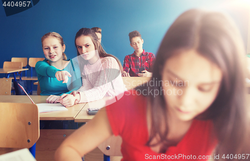 Image of students gossiping behind classmate back at school