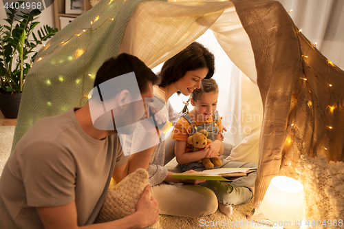 Image of happy family reading book in kids tent at home