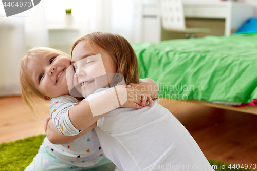 Image of happy little girls or sisters hugging at home