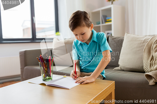 Image of boy with notebook and pencils drawing at home