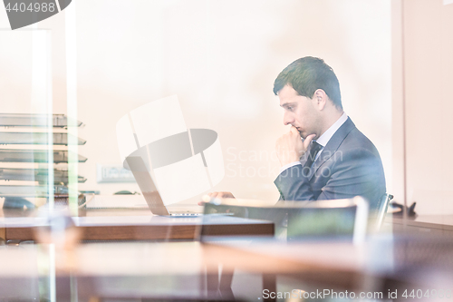 Image of Businessman in office working on laptop computer.