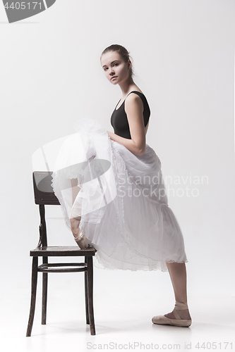 Image of The teen ballerina in white pack posing near chair