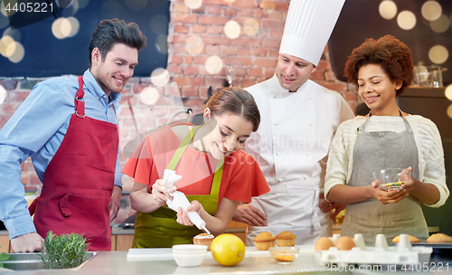 Image of happy friends and chef cook baking in kitchen