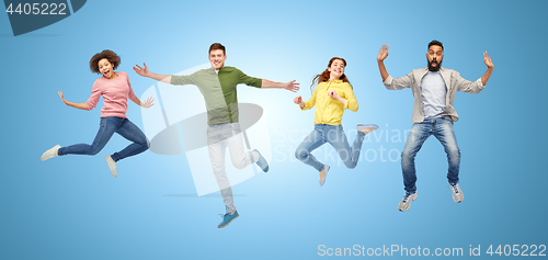 Image of happy people or friends jumping in air over blue