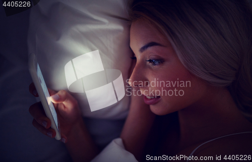 Image of young woman with smartphone in bed at home bedroom