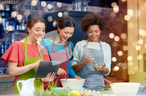 Image of happy women with tablet pc cooking in kitchen