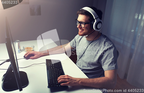 Image of man in headset playing computer video game at home