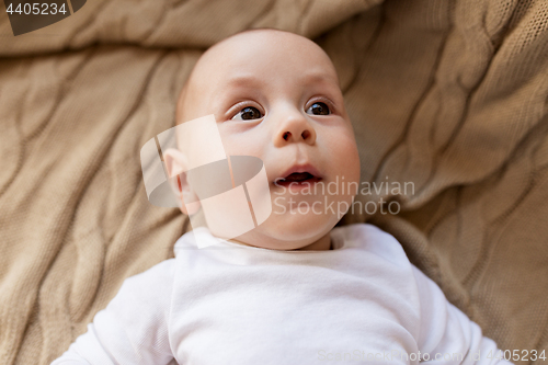 Image of sweet little baby boy lying on knitted blanket