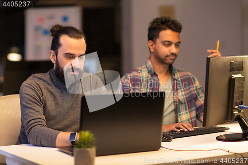 Image of creative team with computer working late at office