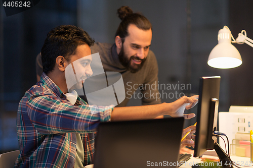 Image of creative team with computer working late at office