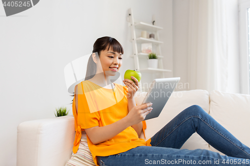 Image of happy asian woman with tablet pc and apple at home