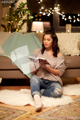 Image of happy young woman reading book at home