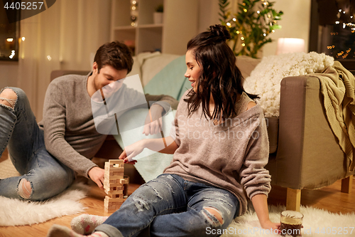 Image of happy couple playing block-stacking game at home