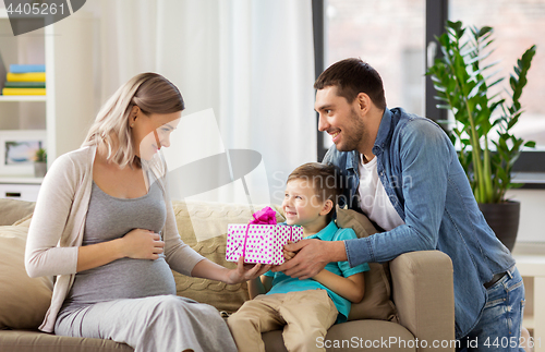 Image of family giving present to pregnant mother at home