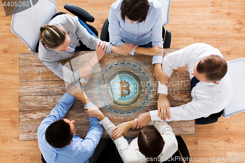 Image of business team with bitcoin hologram holding hands