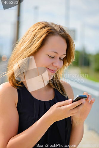 Image of Young cheerful beautiful female using mobile phone