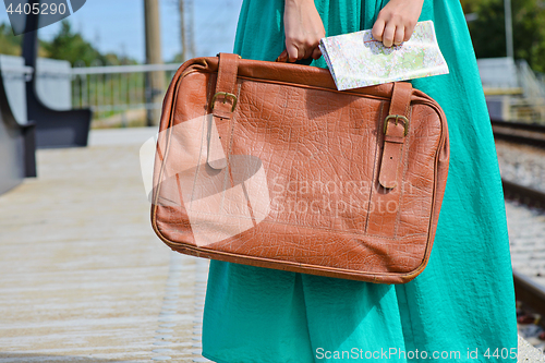 Image of Girl in a holding a map and suitcase at station